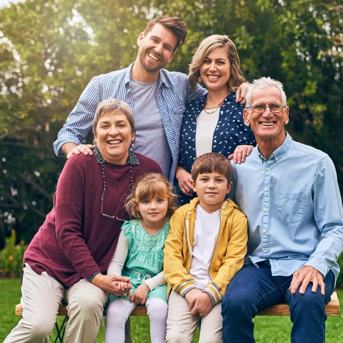 Family of five sitting on a bench in a park, and posing for a photo