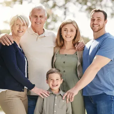 Family of four, two adults and two children, standing in a park and for a photo