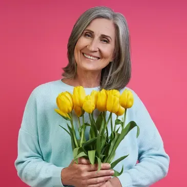 Woman with a bright smile on her face, holding a bouquet of yellow tulips in her hands