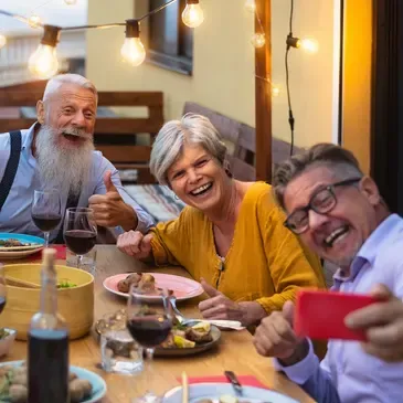 Three older people sitting around a table, and taking a selfie
