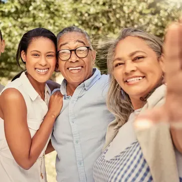 Family of four, a man and two women, and posing for a photo in front of a backdrop of trees