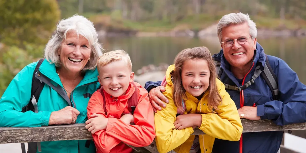 Family of four - a man, woman and two children - standing on a bridge, and posing for a photo