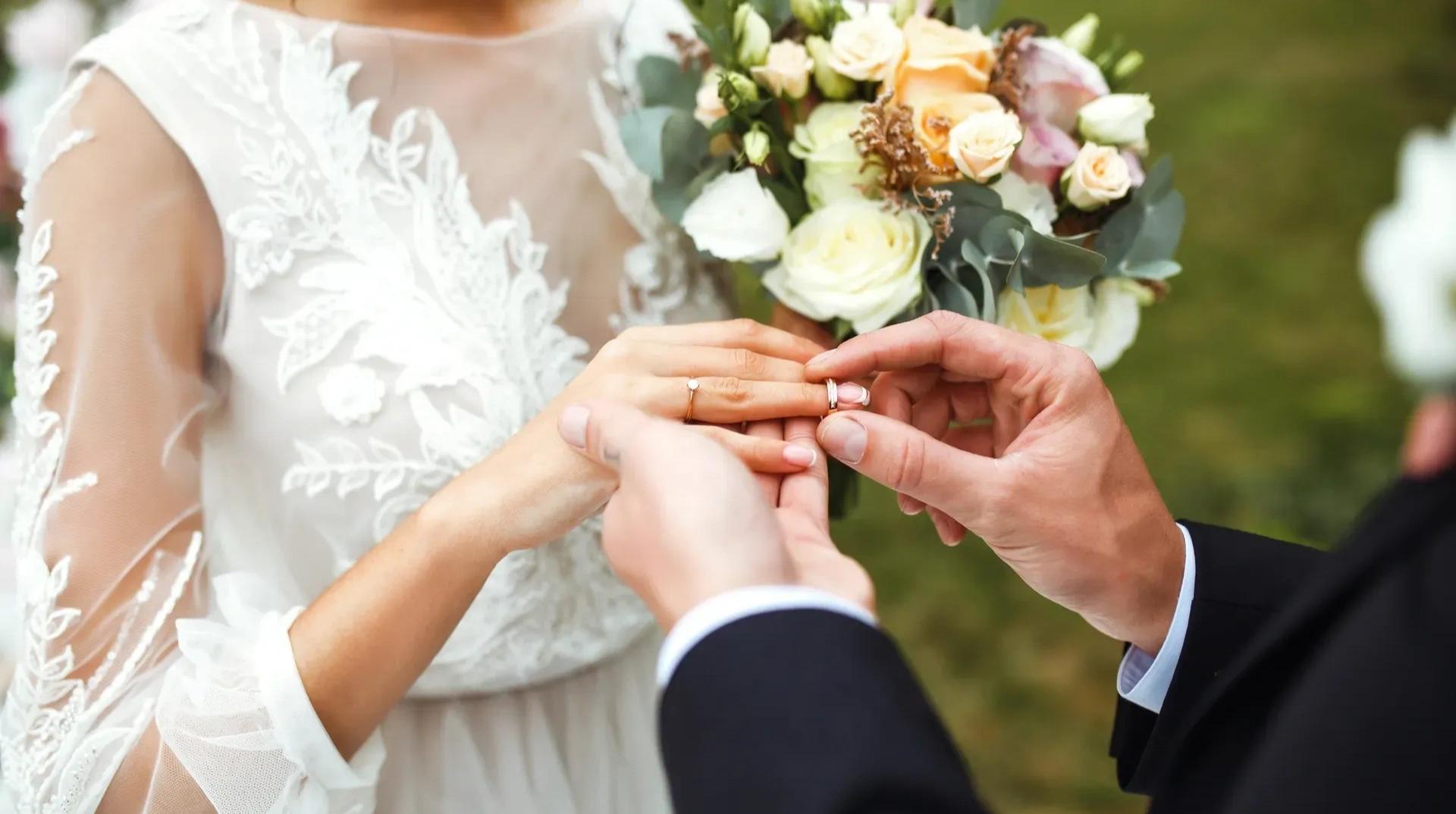 Bride and groom exchanging their wedding rings, with the bride holding a bouquet of flowers