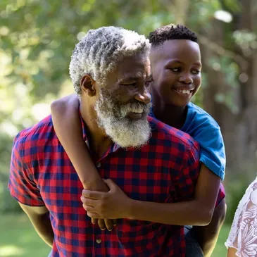 Older man wearing a red and shirt, holding a boy in his arms