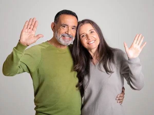 Man and woman standing and with their hands up in the air, against a white background